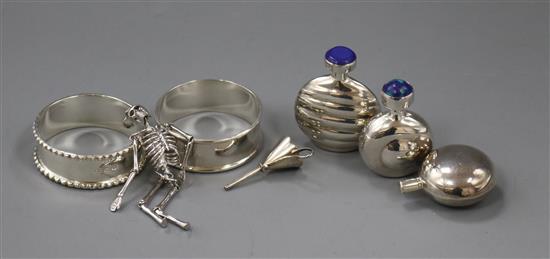 Two silver napkin rings, a skeleton charm and three silver scent flasks.